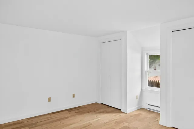 a view of an empty room with closet and a window