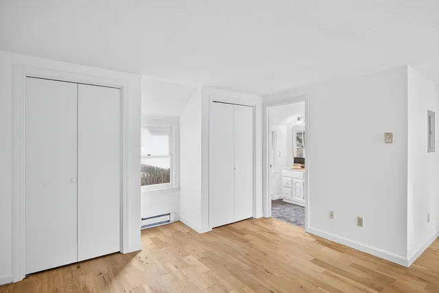 a view of an empty room with wooden floor and a bathroom