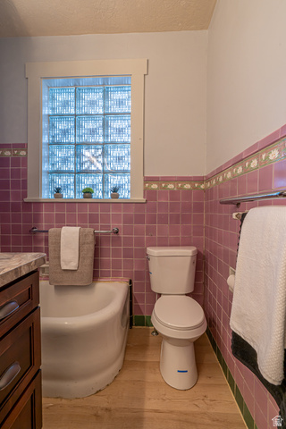33 North 200 East Logan, UT 84321 - Photo 18 of 54 Full bath with a wainscoted wall, vanity, a bath, tile walls, and light wood-style flooring