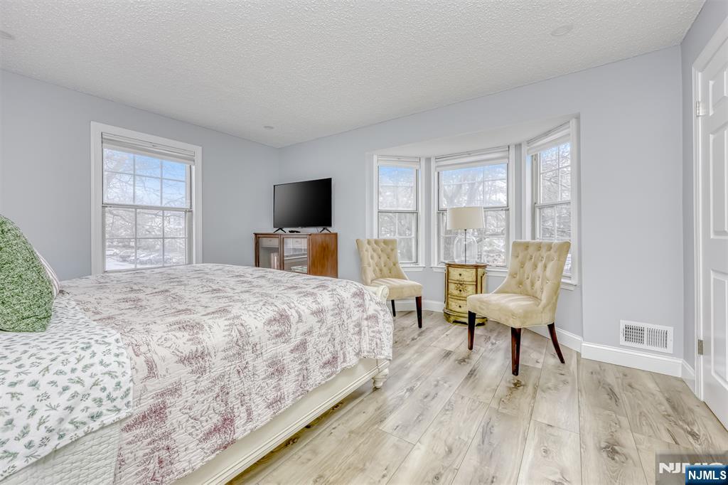 667 Juniper Way, Unit 667 Mahwah, NJ 07430 - Photo 9 of 14 a bedroom with a bed a large window and a flat screen tv