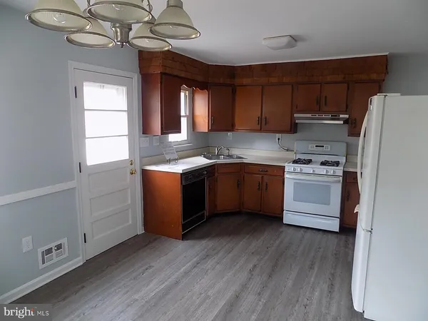 a kitchen with stainless steel appliances granite countertop a sink a stove a refrigerator with wooden floors and cabinets