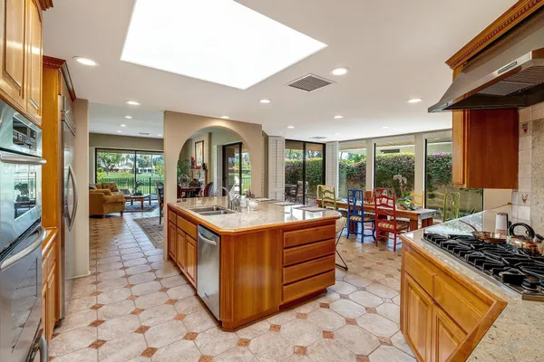 a large kitchen with stainless steel appliances granite countertop a stove and a view of living room
