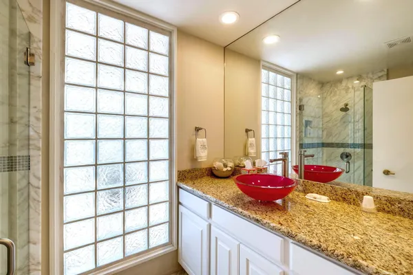 a bathroom with a granite countertop sink and large window