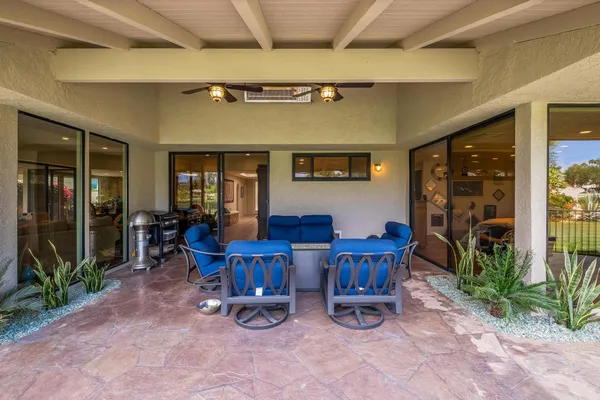 a view of a patio with table and chairs potted plants and floor to ceiling window