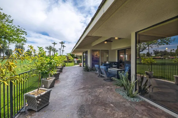 a view of a patio with table and chairs potted plants and floor to ceiling window