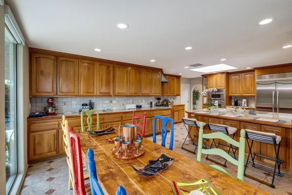 a kitchen with stainless steel appliances granite countertop a stove top oven a sink a dining table and chairs with wooden floor