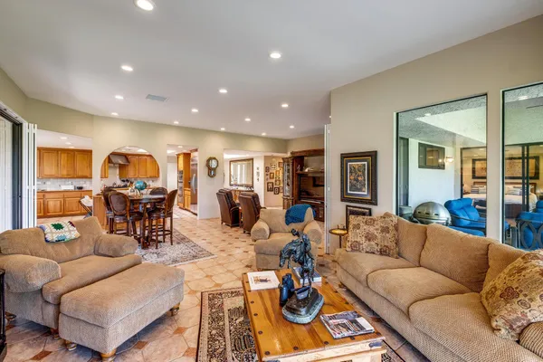a living room with furniture kitchen view and a wooden floor