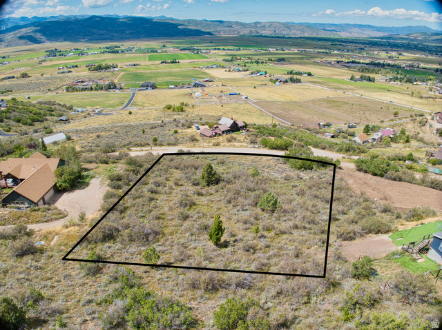Expansive property featuring natural vegetation, mature trees, and mountainous terrain in the background