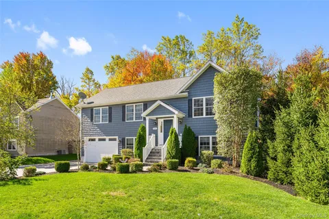 a front view of a house with a garden and trees