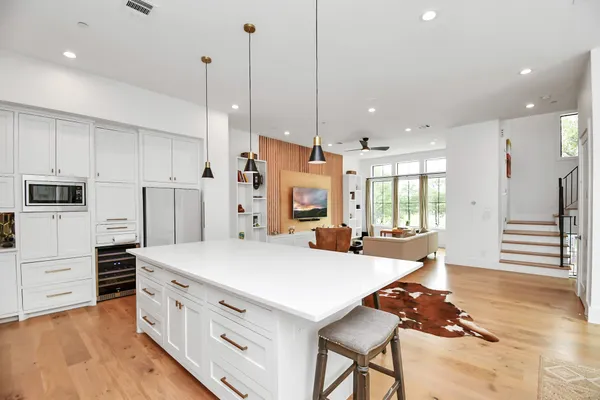a kitchen with stainless steel appliances kitchen island granite countertop a refrigerator a stove and white cabinets with wooden floors