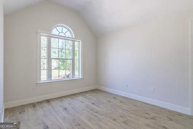 an empty room with wooden floor chandelier and window