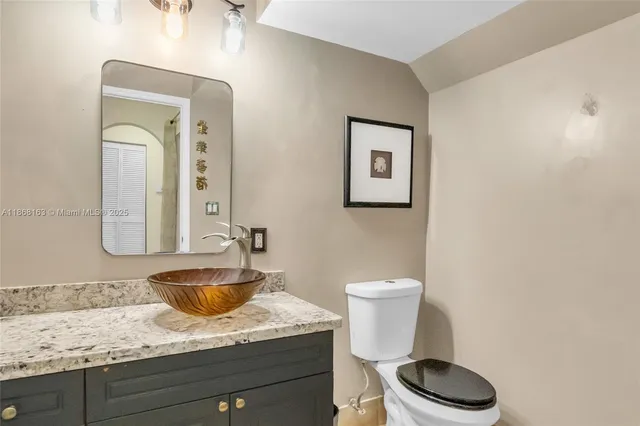 a bathroom with a granite countertop toilet sink and mirror