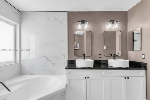 a bathroom with double vanity sinks and a bathtub