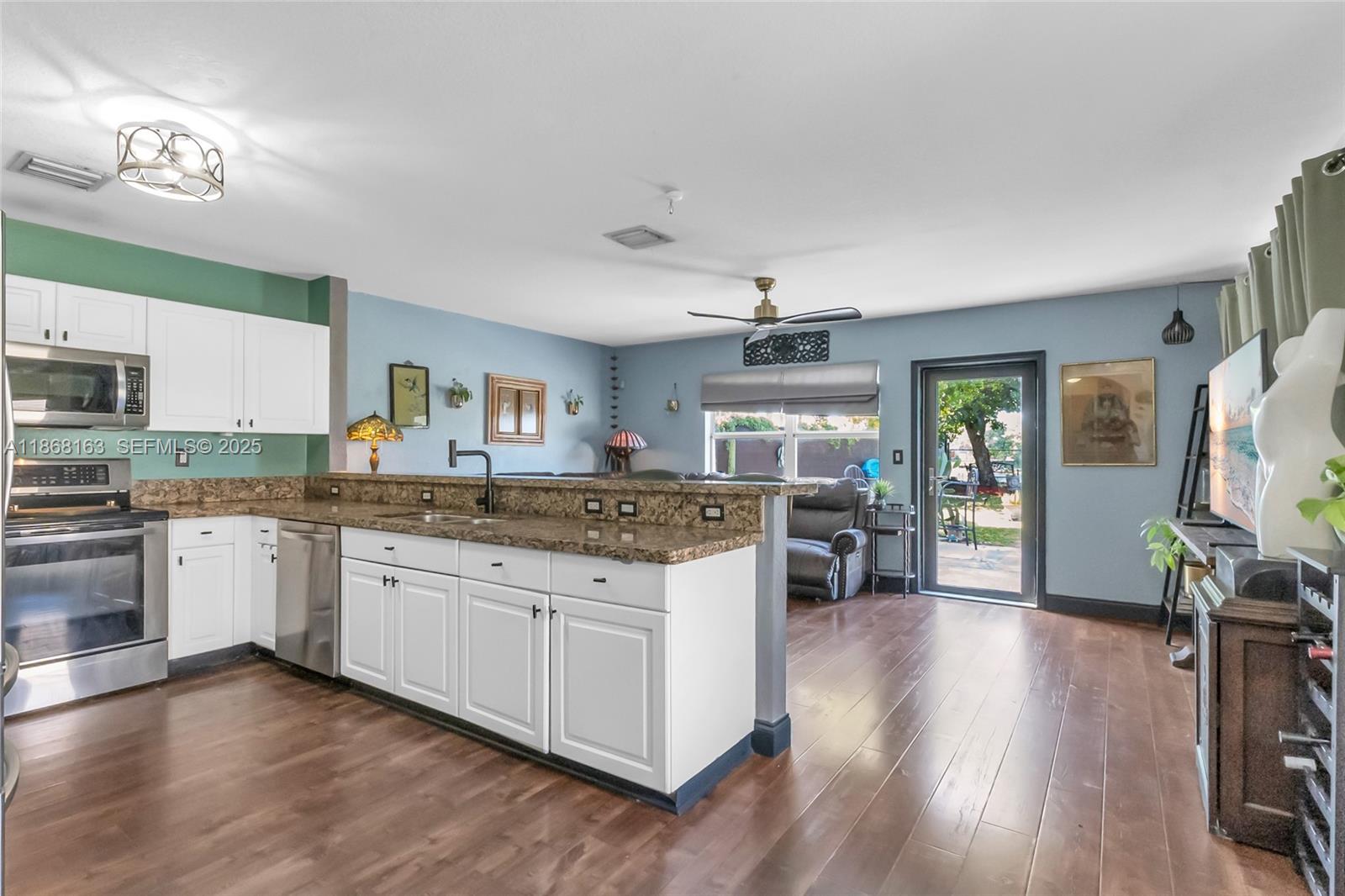 12160 Southwest 135th Terrace Miami, FL 33186 - Photo 7 of 46 a kitchen with stainless steel appliances granite countertop wooden floors and view living room