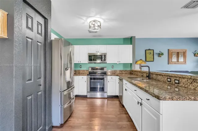a kitchen with granite countertop a sink stainless steel appliances and cabinets