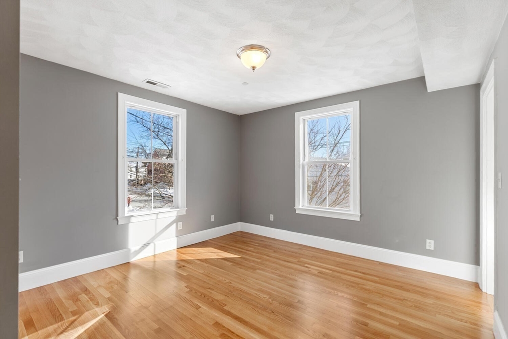 8 Common Street, Unit 3 Stoneham, MA 02180 - Photo 11 of 29 a view of an empty room with wooden floor and a window