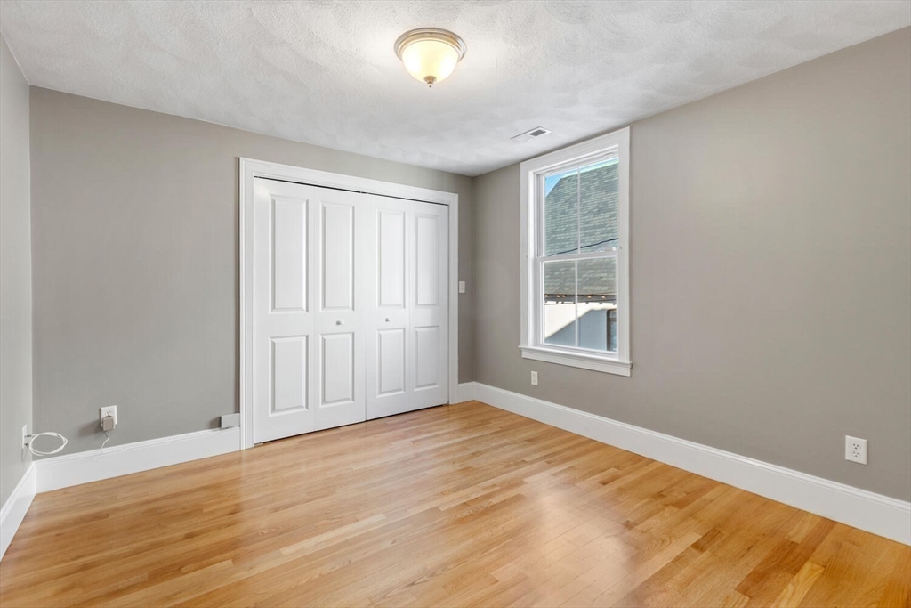 8 Common Street, Unit 3 Stoneham, MA 02180 - Photo 15 of 29 a view of an empty room with wooden floor and a window