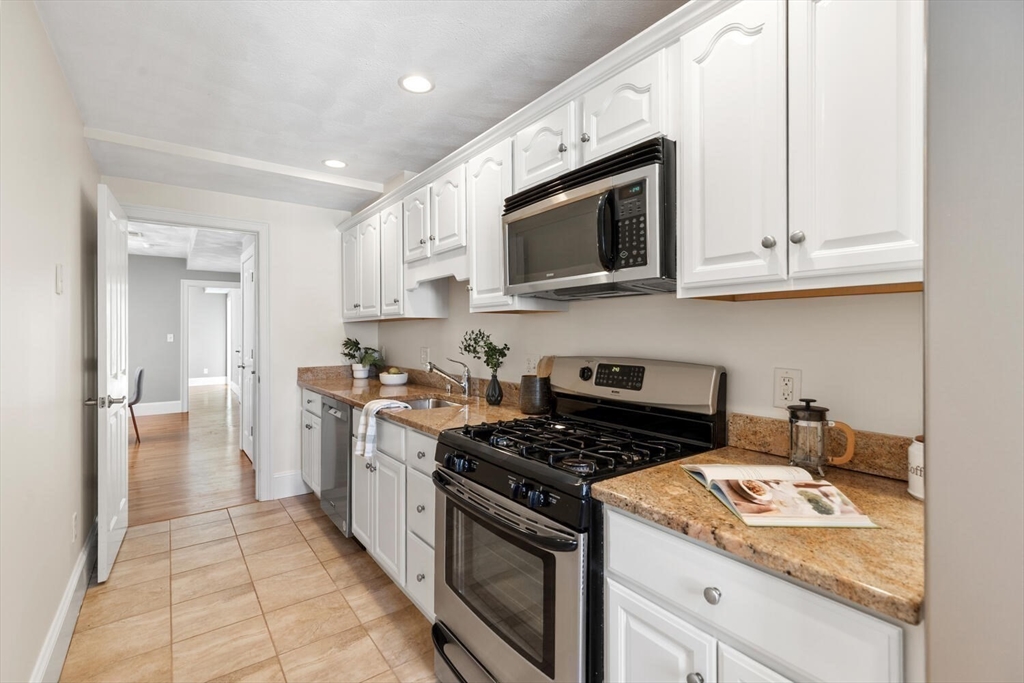 8 Common Street, Unit 3 Stoneham, MA 02180 - Photo 3 of 29 a kitchen with stainless steel appliances granite countertop white cabinets a stove top oven a sink and dishwasher
