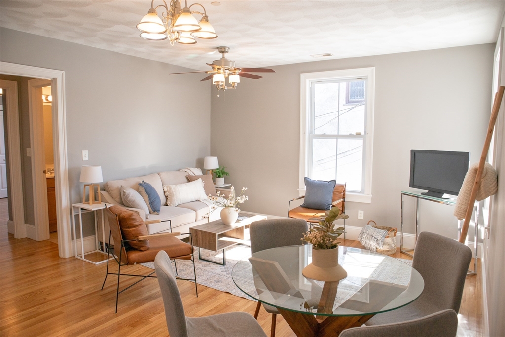 8 Common Street, Unit 3 Stoneham, MA 02180 - Photo 4 of 29 a dining room with wooden floor a chandelier a glass table and chairs