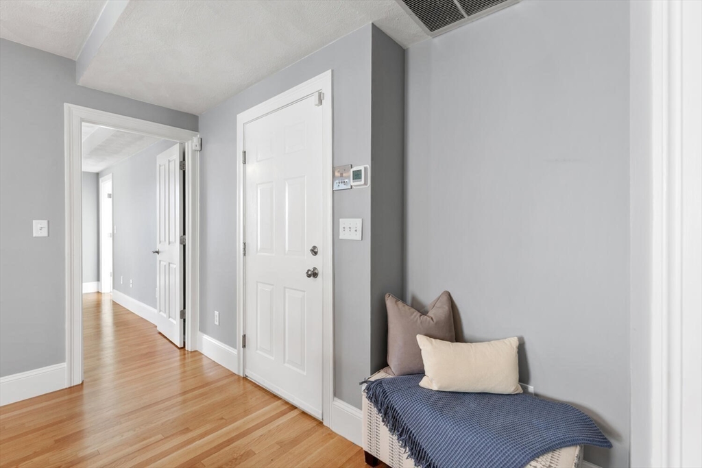 8 Common Street, Unit 3 Stoneham, MA 02180 - Photo 10 of 29 a hallway with wooden floor and a chair