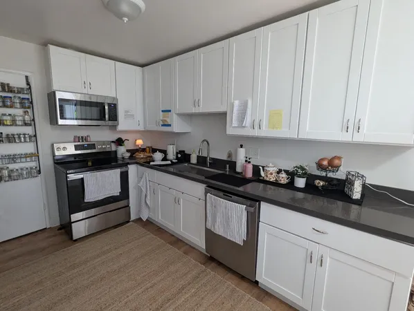 a kitchen with granite countertop white cabinets and stainless steel appliances