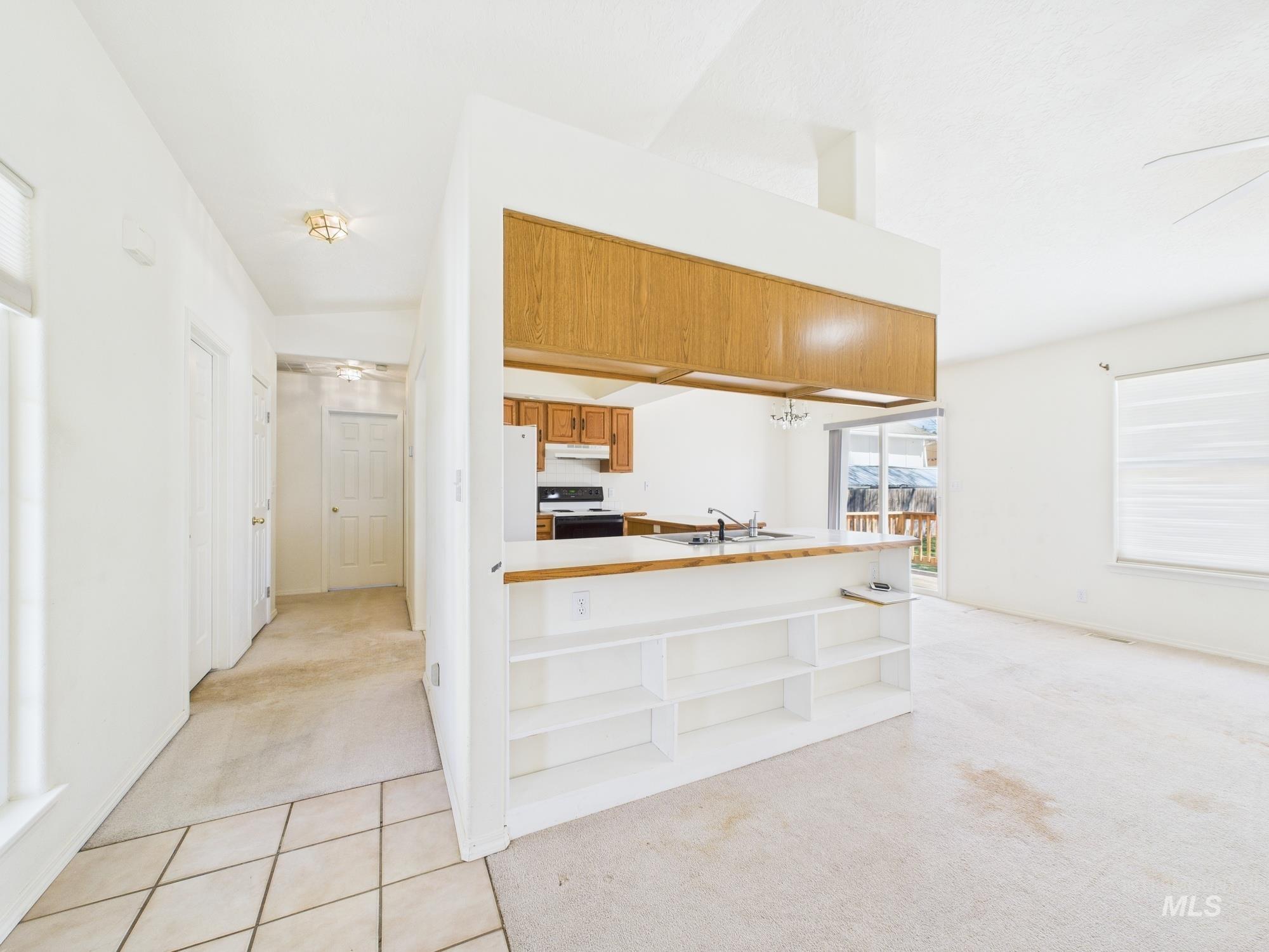 1786 North Plaza Road Emmett, ID 83617 - Photo 5 of 36 Kitchen featuring light colored carpet, light countertops, open shelves, a ceiling fan, and brown cabinets