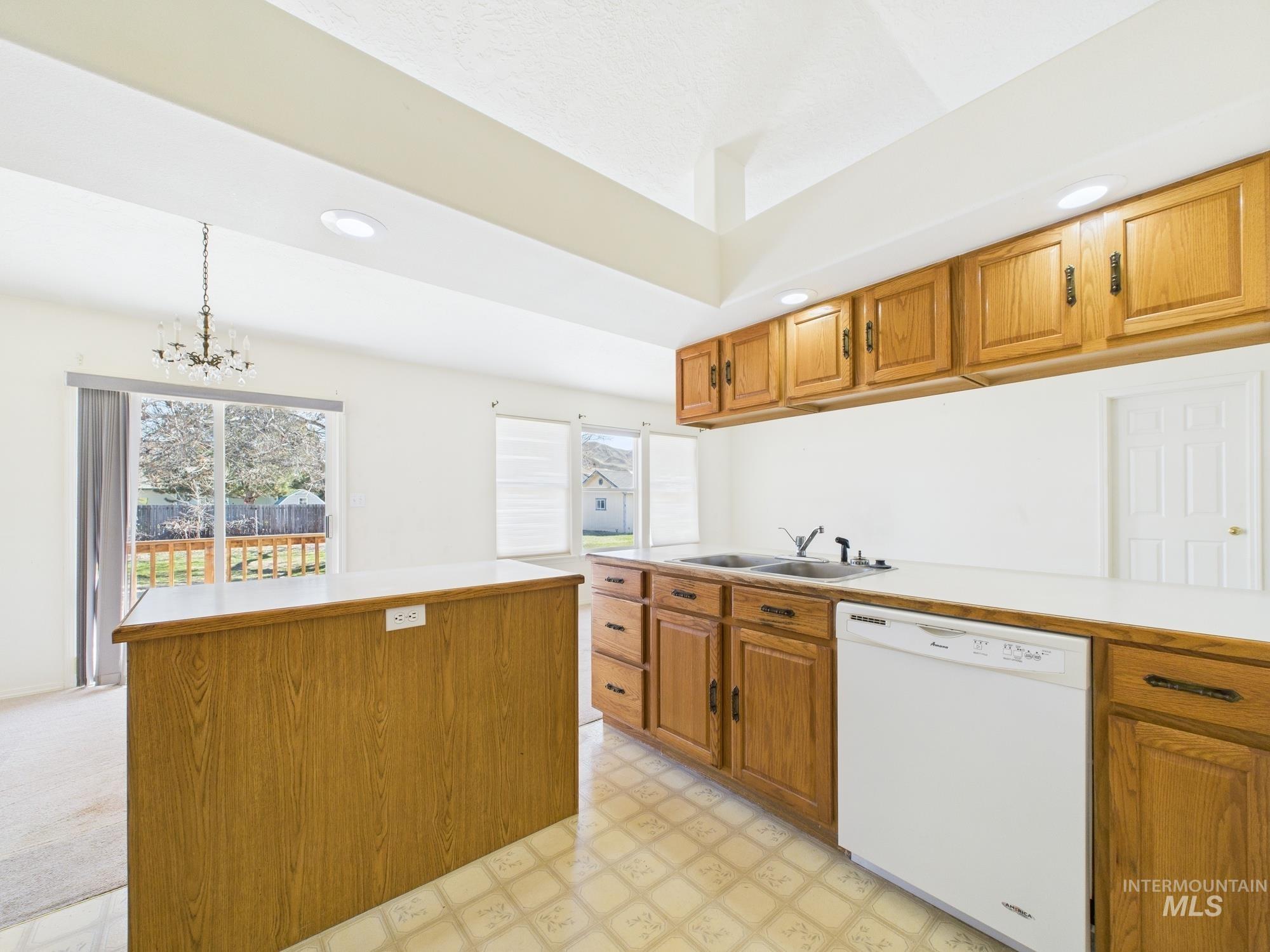 1786 North Plaza Road Emmett, ID 83617 - Photo 7 of 36 Kitchen with light floors, brown cabinetry, white dishwasher, light countertops, and a chandelier