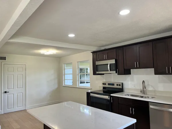 a kitchen with a sink a stove top oven a refrigerator cabinets and a window