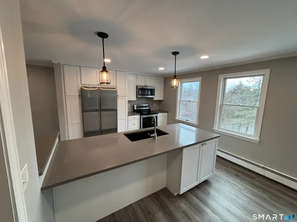 a kitchen with kitchen island a counter top space stainless steel appliances and a window