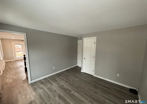 a view of an empty room with wooden floor and a large window