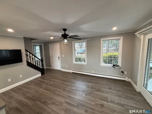 a view of an empty room with a window and wooden floor