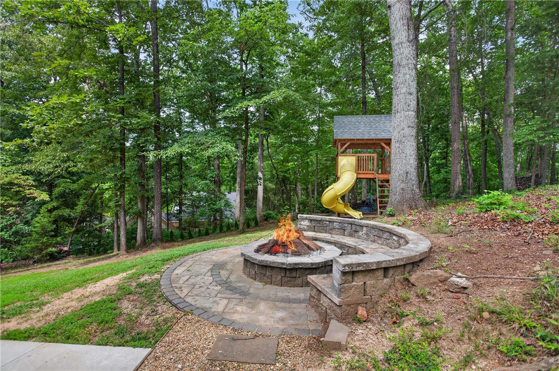 136 Loran Pointe Circle Seneca, SC 29672 - Photo 42 of 50 Enjoy evening gatherings by the fire pit with a children's playset tucked into the verdant woods.