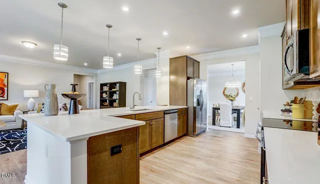 a large kitchen with kitchen island a stove a sink a refrigerator and a dining table with wooden floor