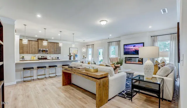 a living room with stainless steel appliances kitchen island granite countertop furniture a rug a fireplace and a kitchen view