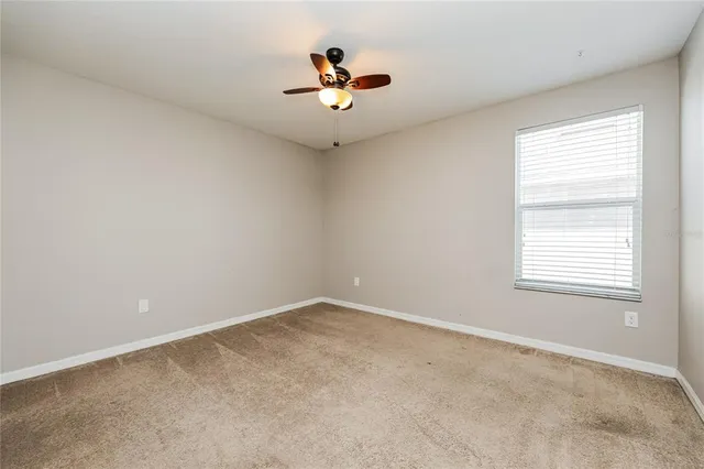 an empty room with a window and a ceiling fan