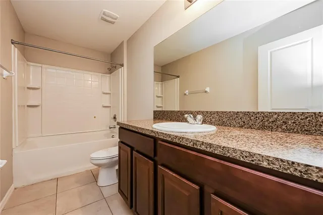 a bathroom with a granite countertop sink a toilet and shower