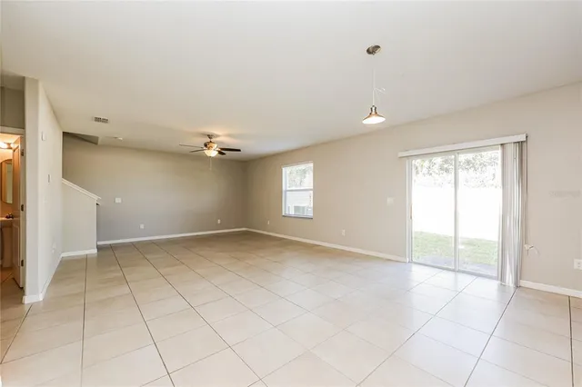 an empty room with windows and ceiling fan