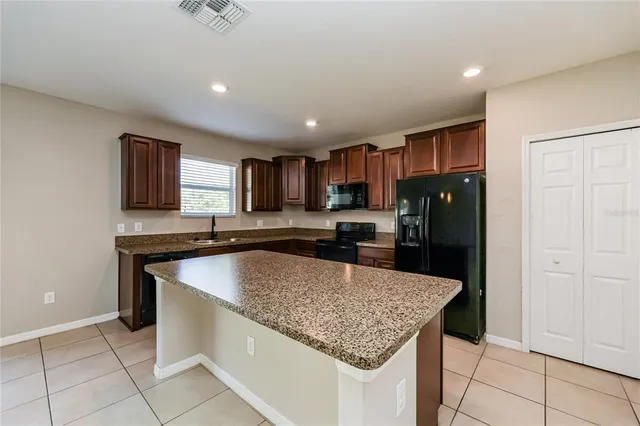 a kitchen with granite countertop stainless steel appliances a sink stove and refrigerator