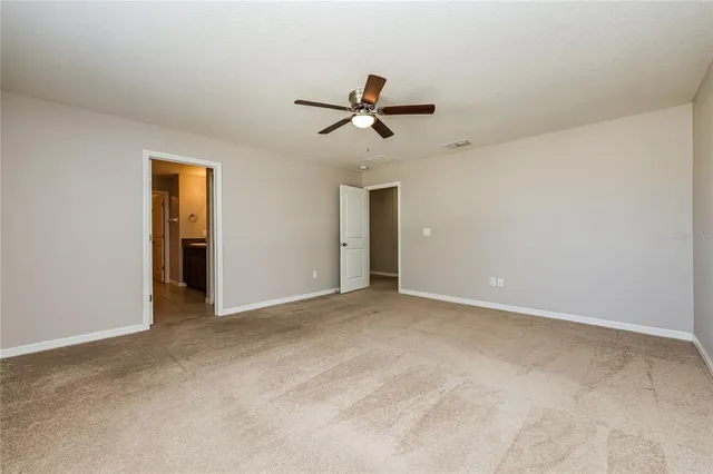 an empty room with closet and a ceiling fan