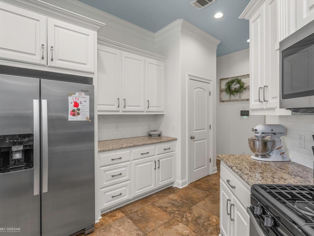 690 Lessie Drive Stonewall, LA 71078 - Photo 11 of 29 Modern kitchen featuring white cabinetry, granite countertops, a subway tile backsplash, stainless steel appliances, and large format floor tiles