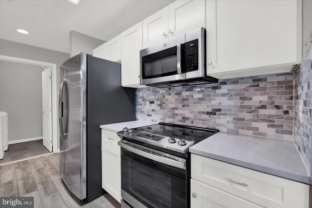 a kitchen with stainless steel appliances white cabinets and a stove top oven