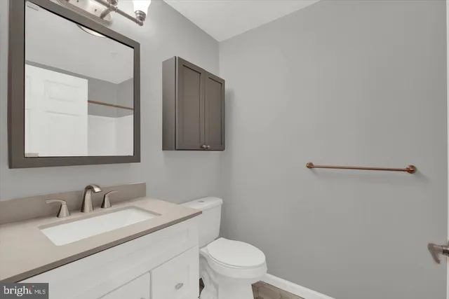 a bathroom with a granite countertop sink mirror vanity and toilet