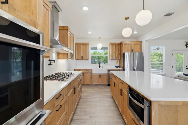 a large kitchen with stainless steel appliances granite countertop a stove and a sink