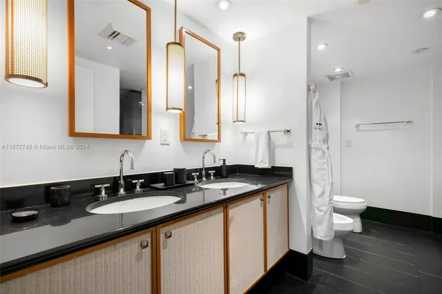a bathroom with a granite countertop sink a toilet a mirror and a shower