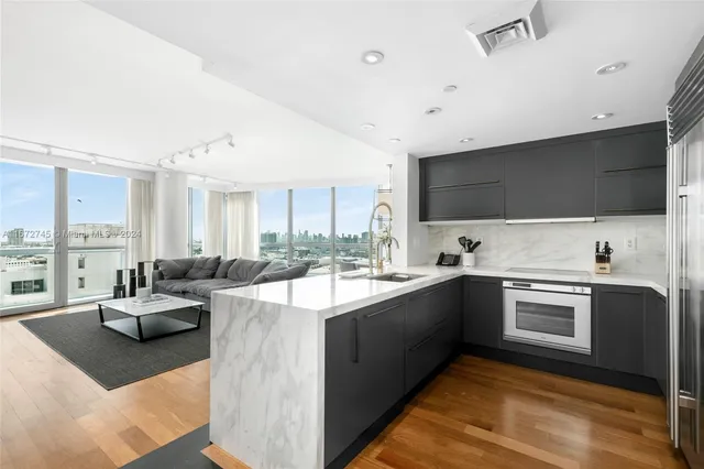 a large white kitchen with a large window and stainless steel appliances