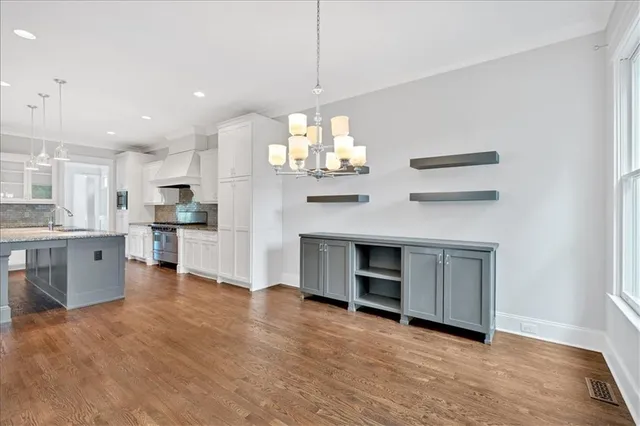 a view of an empty room with kitchen and window