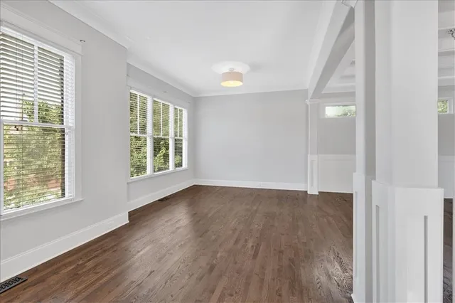 a view of an empty room with chandelier and wooden floor