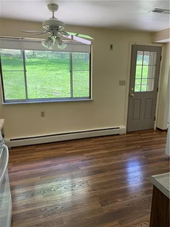 a view of empty room with wooden floor and fan