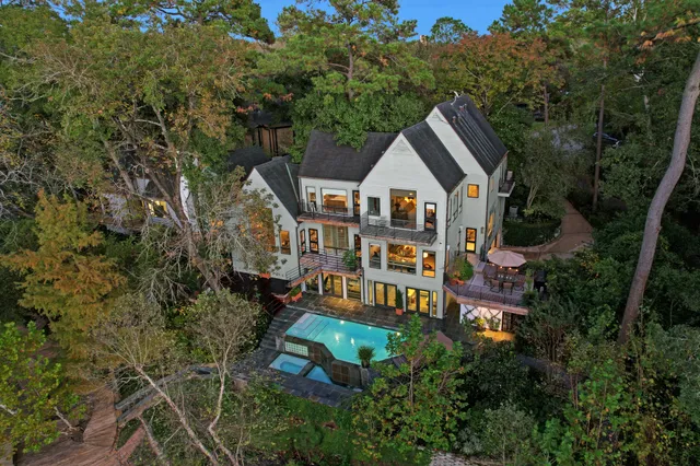 an aerial view of a house with balcony and trees al around