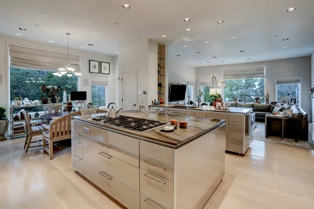 a kitchen with kitchen island a large counter top space a sink stainless steel appliances and cabinets